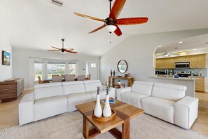 A spacious living area with a large white sectional sofa, a wooden coffee table with decorative vases, and a ceiling fan. - Marco Island Oasis, Private Pool, Waterfront & Family Fun! (Marco Island)