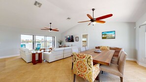 A spacious living area with a large dining table, two ceiling fans, a sofa, and a view of the outdoors. - Marco Island Oasis, Private Pool, Waterfront & Family Fun! (Marco Island)