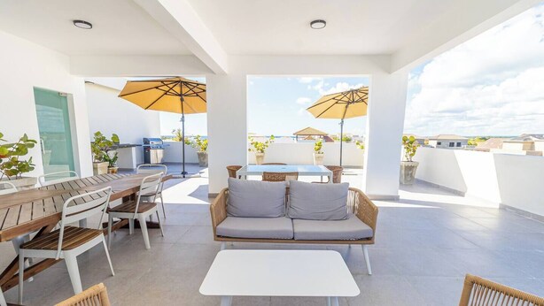Eine Dachterrasse mit Essbereich, Sitzgelegenheiten und Sonnenschirmen.