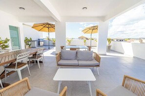 Une terrasse sur le toit comprenant un espace repas, des sièges et des parasols.