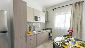 Eine moderne Küche mit integriertem Mikrowellenherd, Spüle aus Edelstahl und einem Essbereich mit Tisch für zwei Personen.