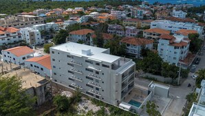 Ein Küstenwohngebiet mit einer Mischung aus modernen und traditionellen Gebäuden, freiem Blick auf das Meer und einem Poolbereich.