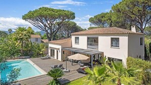 Una villa moderna con piscina, mobiliario exterior y patio cubierto.