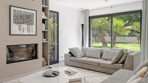 Una sala de estar moderna con un sofá gris, una mesa de centro blanca y una chimenea.