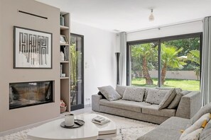 Ein modernes Wohnzimmer mit grauem Sofa, weißem Couchtisch und Kamin.