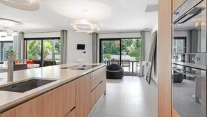 Una cocina moderna con una isla central, ventanas amplias y un comedor con vista a zonas verdes.