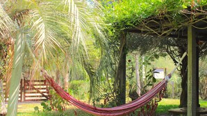 Eine Hängematte in einem Garten mit einer Holz-Pergola, einer Holzbank und einem Holztisch.