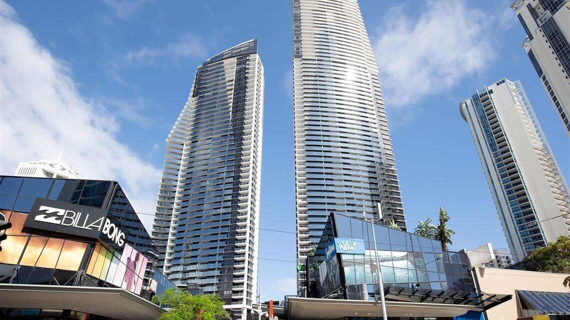 A modern high-rise building with a curved facade, surrounded by other tall buildings and a clear sky.