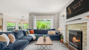 Una sala moderna con un sofá seccional, una chimenea y vistas al exterior.