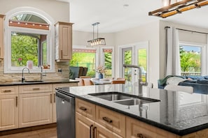 A modern kitchen with a large island, built-in appliances, and large windows offering a view of the outdoors.