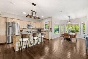 A modern kitchen with a central island, stainless steel appliances, and a dining area with a view.