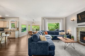 A modern living room with a dark blue sofa, a wooden coffee table, and a fireplace.