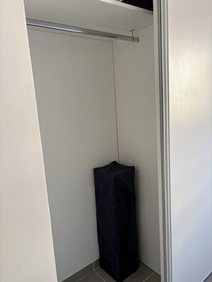 Ein Zimmer mit einer weißen Tür, einem schwarzen Gegenstand auf dem Boden und einer Metallstange an der Decke.
