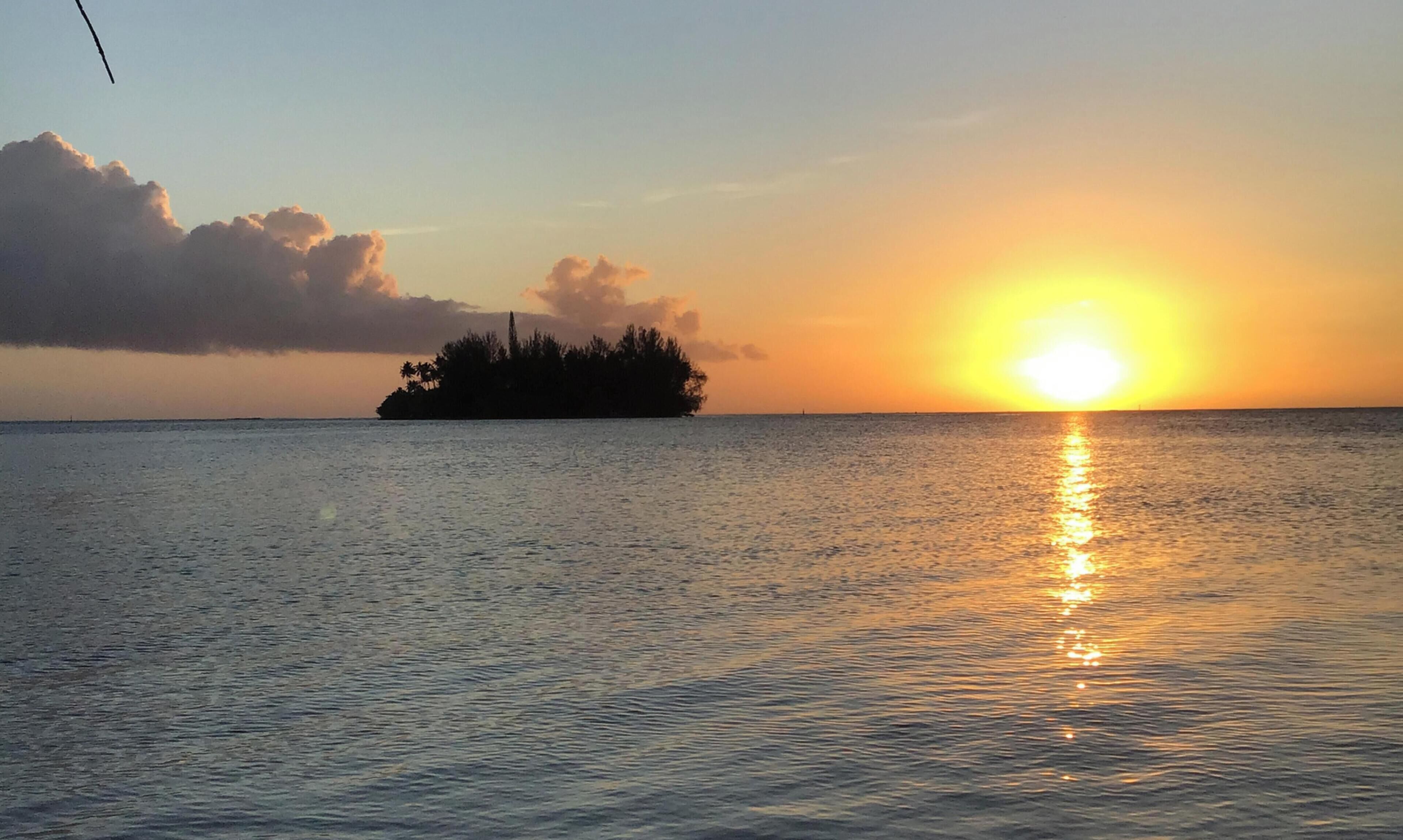 Un atardecer sobre aguas tranquilas con la silueta de una isla.
