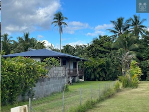 A house with a blue roof, surrounded by lush greenery and palm trees.