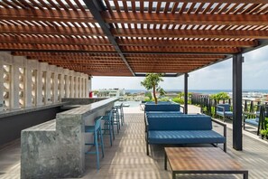 Eine Dachterrasse mit einer Betonbar, blauen Barhocker und blauen Sitzgelegenheiten.