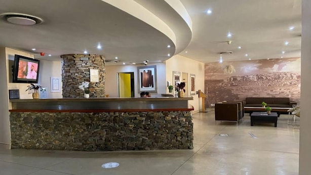 Un espace d’accueil avec un comptoir en pierre, un téléviseur, des tableaux encadrés et une fresque murale.