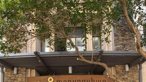 L’entrée d’un hôtel, avec une enseigne indiquant « Mapungubwe Hotel Apartments », une façade en pierre et une grande porte en bois.