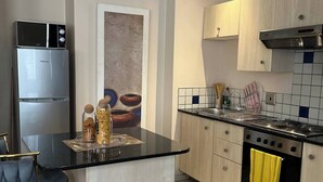 Une cuisine moderne dotée d’un îlot central, d’appareils électroménagers en acier inoxydable et de meubles de rangement en bois clair.
