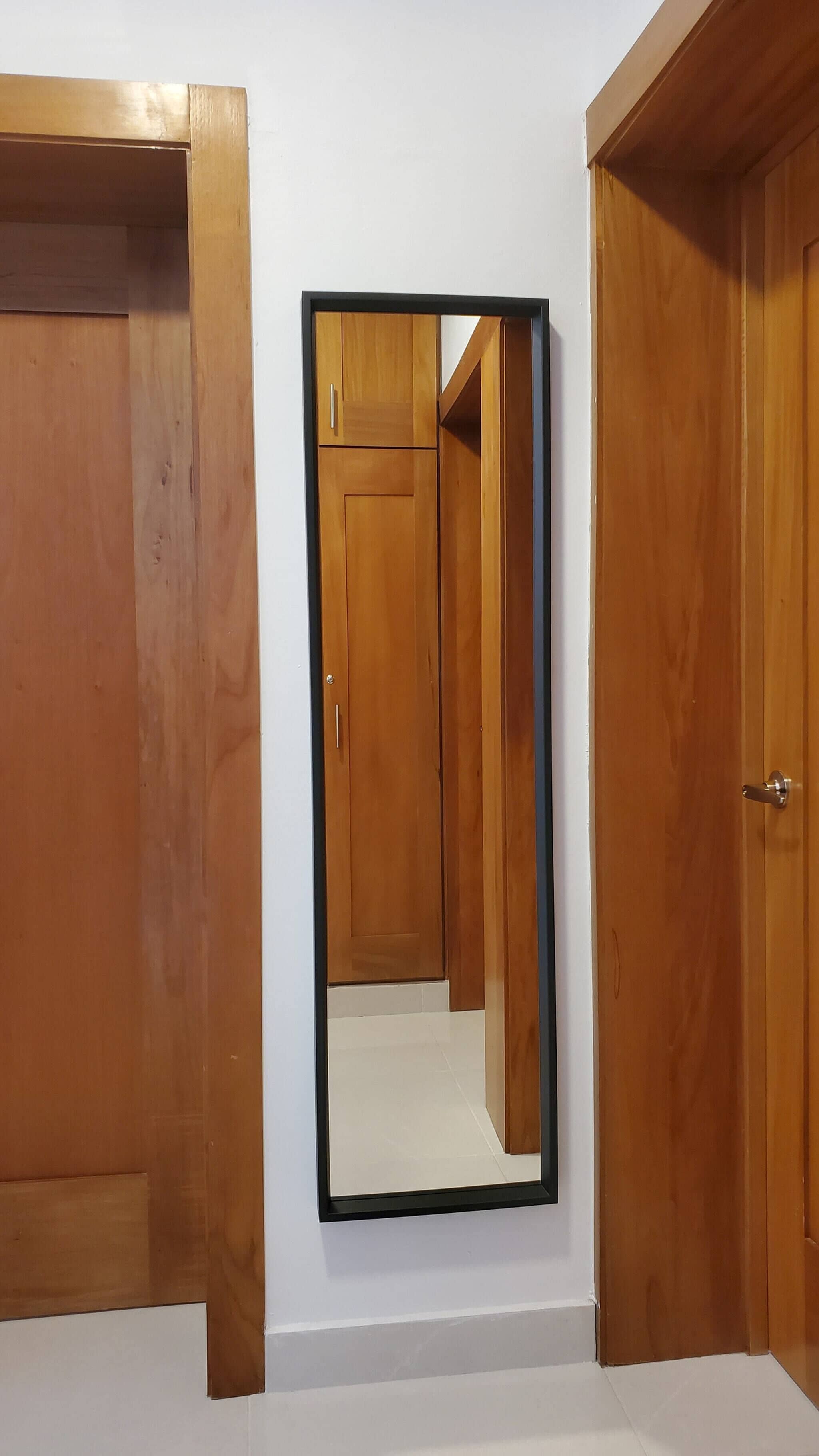 Un pasillo con puertas de madera y un espejo en la pared.