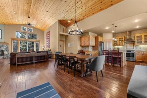 A spacious kitchen with wooden cabinets, a dining area with a large table and chairs, and a ceiling with exposed beams. - Ski Slope Views Tahoe Donner Retreat (Truckee)