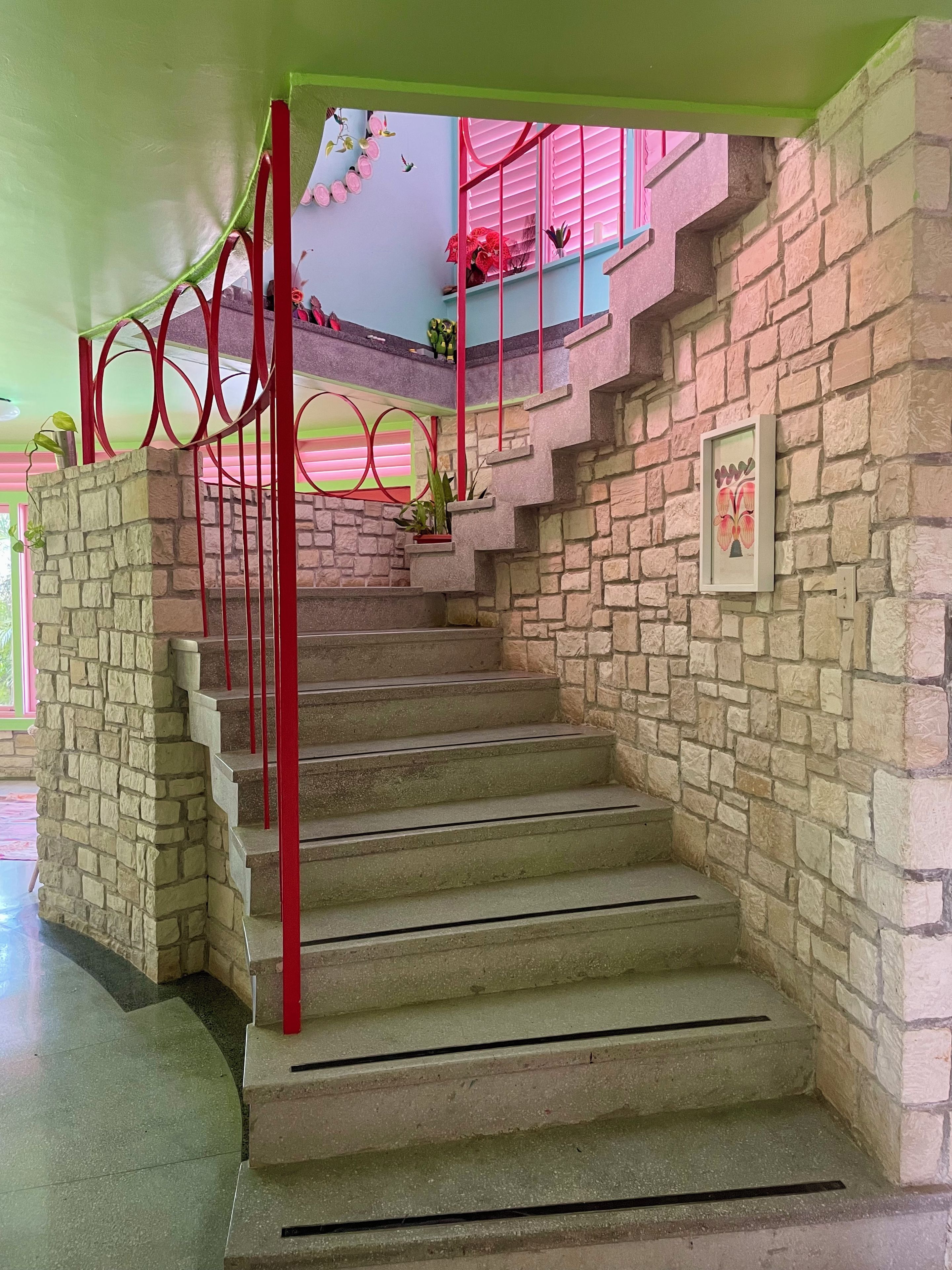 A staircase with red railings and stone walls.