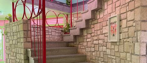 A staircase with red railings and stone walls.