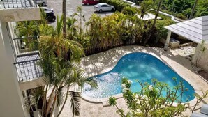 A swimming pool surrounded by palm trees and a building with a balcony. - Cozy 2BR/2Bth walk 2 the beach. Pool view & Wi-Fi (Punta Cana)