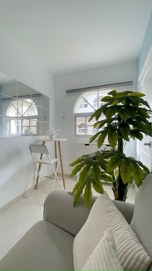 Ein modernes Wohnzimmer mit großem Fenster, Essbereich und einer Topfpflanze.