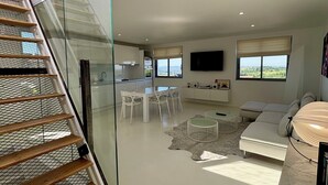 A modern interior with a staircase, dining area, living room, and a TV mounted on the wall. - White Loft - 6 personnes - toit-terrasse avec vue panoramique (Donzenac)