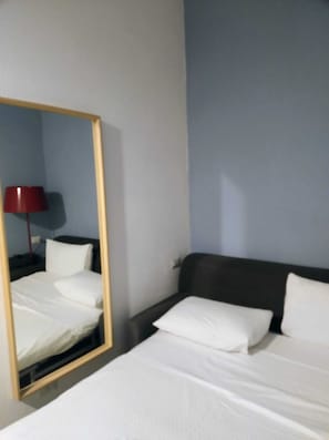 A hotel room with a bed, a nightstand, a lamp, and a mirror. - Chiaja Corner (Naples)