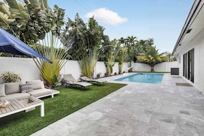 A backyard with a pool, a white wall, and a lawn. - Imperial Point Villa With Pool (Fort Lauderdale)