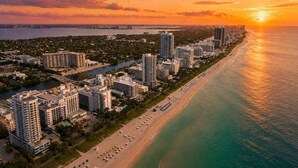 A coastal cityscape with high-rise buildings, a beach, and a sunset. - Luxury Miami Stay with Skyline Balcony (Miami)
