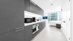 A modern kitchen with grey cabinetry, a microwave, and a coffee maker. - Luxury Miami Stay with Skyline Balcony (Miami)