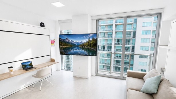 A modern living room with a large TV, a sofa, a coffee table, and a desk with a laptop. - Luxury Miami Stay with Skyline Balcony (Miami)