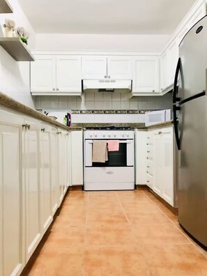 Eine Küche mit weißen Schränken, einem Herd, einer Mikrowelle und einem Kühlschrank.
