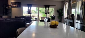 Eine moderne Küche mit Marmorarbeitsplatte, ein Essbereich mit einer Couch und Blick auf den Garten.