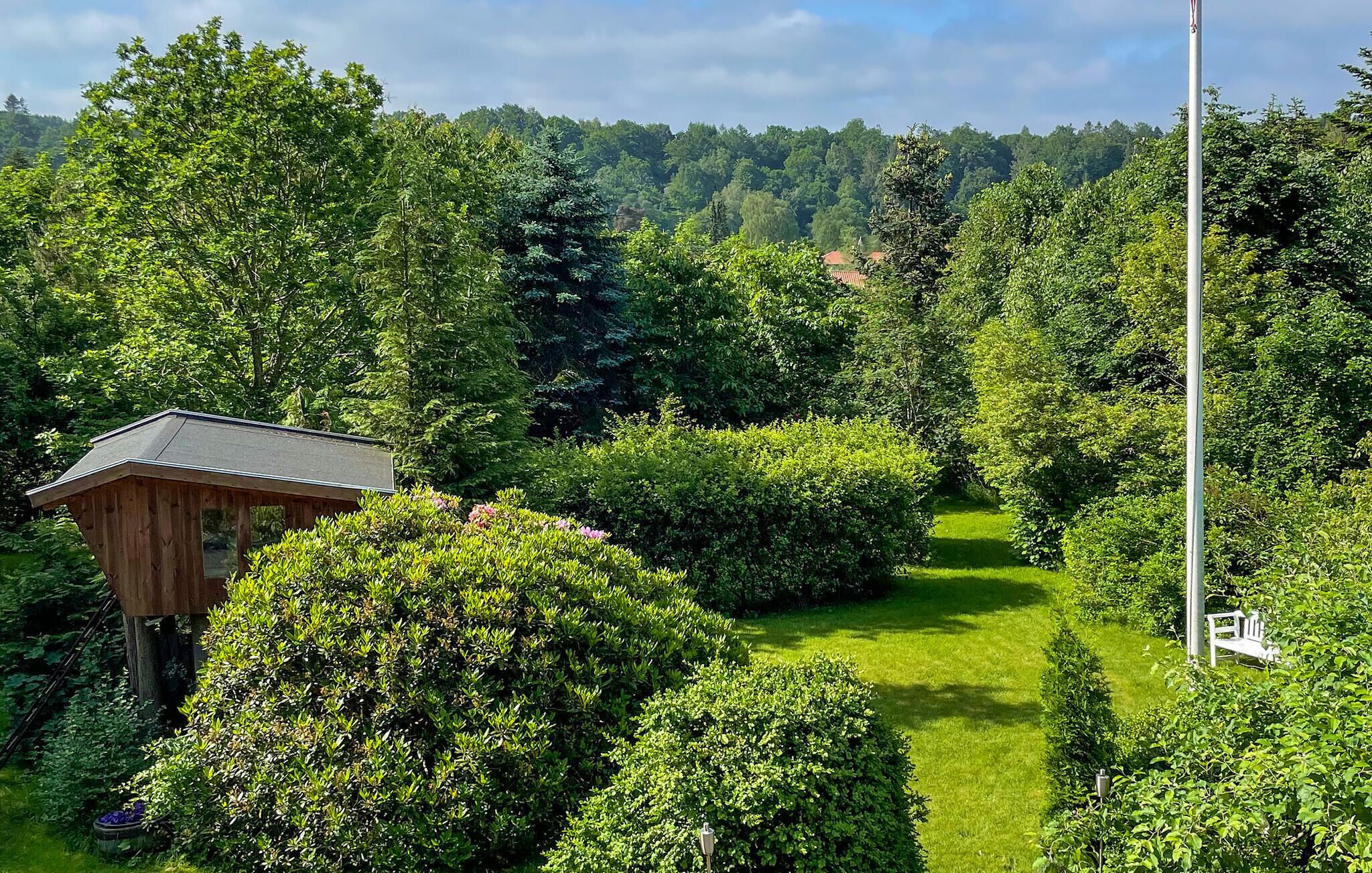 A wooden cabin surrounded by lush greenery and a clear path.