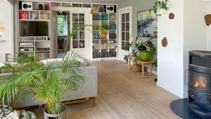 Una sala de estar acogedora con chimenea, estanterías y plantas en macetas.