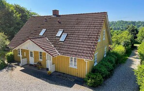 A two-story house with a tiled roof, a front porch, and a gravel driveway. - 3 bedroom beautiful home in Bryrup (Bryrup)