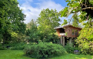 A treehouse with a wooden exterior, surrounded by lush greenery and trees. - 3 bedroom beautiful home in Bryrup (Bryrup)
