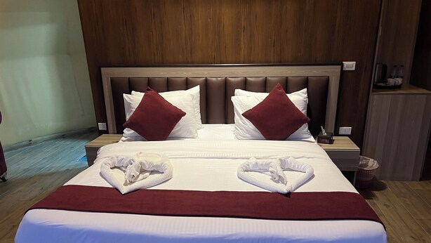 Una habitación de hotel con una cama grande, dos almohadas, una mesita de noche y un letrero que dice 'LUXURY MAGIC'.