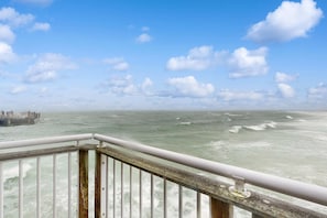 A view from a balcony overlooking a turbulent sea with a clear sky.