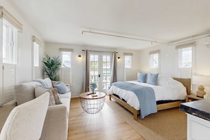 A bedroom with a bed, a sofa, a round side table, and a large window.
