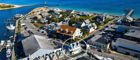 An aerial view of a coastal town with a marina, houses, and a lighthouse.