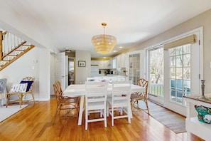 A spacious kitchen with white cabinetry, a dining area with white chairs, and a wooden staircase. - Walk to Grays Beach, Near Shops & Boardwalk (Yarmouth)
