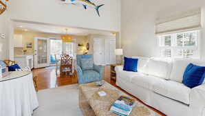 A spacious living area with a high ceiling, a dining table, a white sofa, and a decorative fish hanging from the ceiling. - Walk to Grays Beach, Near Shops & Boardwalk (Yarmouth)