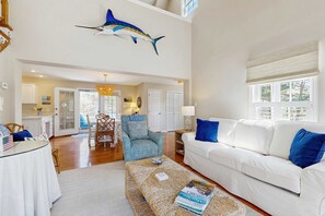 A spacious living area with a high ceiling, a dining table, a white sofa, and a decorative fish hanging from the ceiling. - Walk to Grays Beach, Near Shops & Boardwalk (Yarmouth)