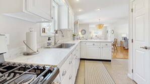 A modern kitchen with white cabinetry, a stainless steel sink, and a gas stove. - Walk to Grays Beach, Near Shops & Boardwalk (Yarmouth)