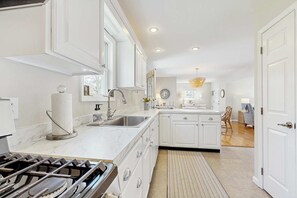 A modern kitchen with white cabinetry, a stainless steel sink, and a gas stove. - Walk to Grays Beach, Near Shops & Boardwalk (Yarmouth)